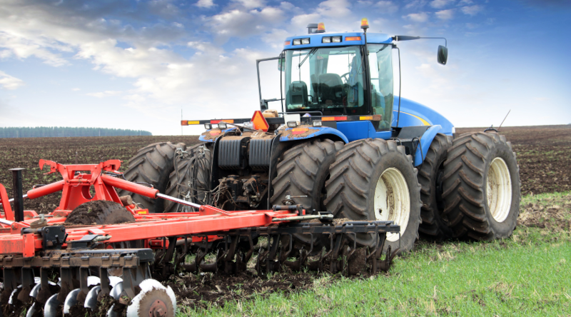 En traktor med fulde vinduer, der pløjer en mark